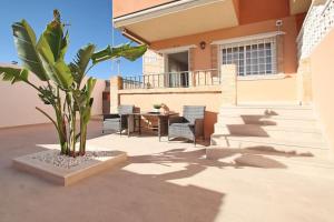 une terrasse avec une table et un palmier dans l'établissement Casa Olivia with pool heating fee, à Torrevieja