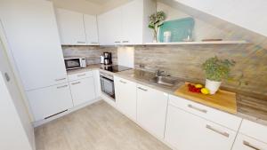 eine Küche mit weißen Schränken und einer hölzernen Arbeitsplatte in der Unterkunft Grüntal-Residenz Haus I App. 7 in Grömitz