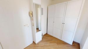 グレーミッツにあるGrüntal-Residenz Haus I App. 7の白いキャビネットと鏡が備わる廊下