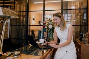 a woman in a white dress typing on a laptop at Boutique Hotel Goud En Zilver in Gorinchem