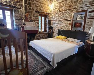 1 dormitorio con cama y pared de piedra en Villa Tzeni Palios Panteleimon en Panteleímon
