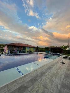 a large swimming pool with a cloudy sky above it at Encanto Cafetero Montenegro in Pueblo Tapao