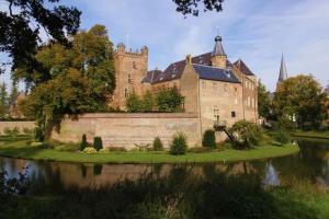 a large castle with a lake in front of it at Cosy apartment in the centre of fortified town Groenlo in Groenlo