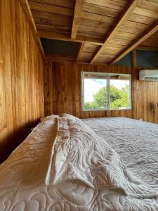 a large bed in a wooden room with a window at La vida en el paraiso BORA BORA in Villavicencio