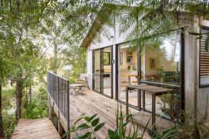 a house with a wooden deck with a table at Craicor Boutique Apartments in Paihia