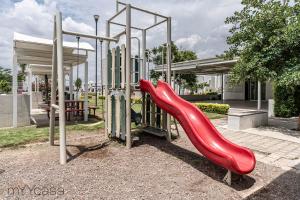 um parque infantil com um escorrega vermelho num parque em Espaciosa Casa Moderna c/ Patio Privado em Aguascalientes