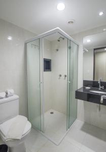 uma casa de banho com um chuveiro, um WC e um lavatório. em Hotel Guarumar Gold no Guarujá