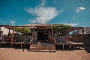 a hut on the beach with benches and trees at Rancheria Utta in Cabo de la Vela