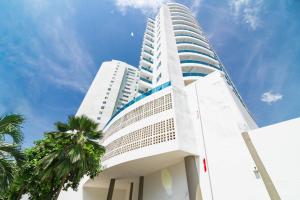 a tall white building with palm trees in front of it at Unik Cartagena Edificio Poseidon in Cartagena de Indias