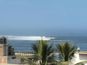 een uitzicht op de oceaan vanuit een gebouw met palmbomen bij Huanchaco Surf Camp in Huanchaco