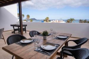 Una mesa de madera con sillas y una mesa con copas de vino. en Luxury Apartments Sea Sabi con garaje, en Corralejo