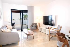 Una sala de estar con un sofá y sillas y un televisor. en Luxury Apartments Sea Sabi con garaje, en Corralejo