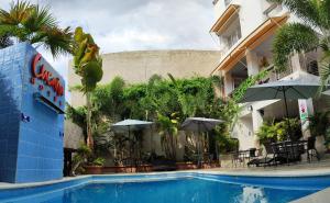El Pedregal的住宿－Cucaña Hotel，酒店前方的游泳池配有桌子和遮阳伞