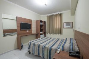 a hotel room with a bed and a television at Hotel Guarumar Gold in Guarujá