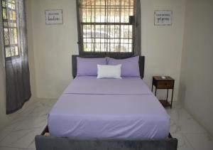 a bed with purple sheets and a pillow on it at Villa Cherry in Gros Islet