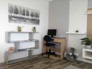 ein Büro mit einem Schreibtisch, einem Stuhl und einem Ventilator in der Unterkunft Apartamento T1 46B in Lagoa