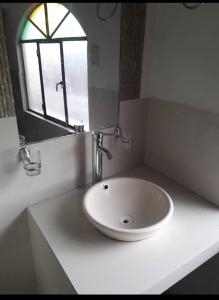 lavabo blanco en un baño con ventana en HOTEL ANAHÍ, en Chulumani