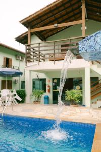 a pool with a water fountain in front of a house at Hotel Kiribati Maresias in Maresias