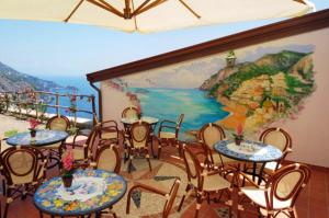 a room with tables and chairs and a painting on the wall at Locanda Degli Dei in Praiano