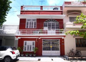 una casa roja y blanca con un coche blanco aparcado delante en Villa Dumont en Pondicherry