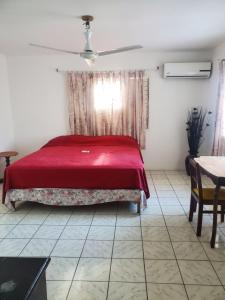 1 dormitorio con cama roja y mesa en Evelin's On The Beach en Montego Bay
