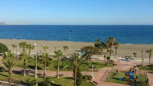 un parque con parque infantil y una playa con el océano en Hotel Miraya Beach, en Torre del Mar