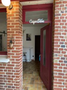 a brick building with a red door and a sign at La fermette: Logis indépendant proche d'Arras sur cours au carré in Achicourt