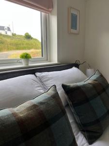 uma cama com duas almofadas num quarto com uma janela em Island Coorie em Kilmaluag