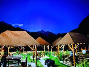 a group of tables and umbrellas with mountains in the background at Guesthouse Villa Gurra in Theth