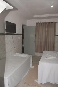 a hotel room with two beds and a flat screen tv at Hostel Adriana Alves in Porto De Galinhas
