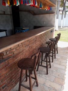 a row of wooden stools sitting at a bar at Hostel Adriana Alves in Porto De Galinhas