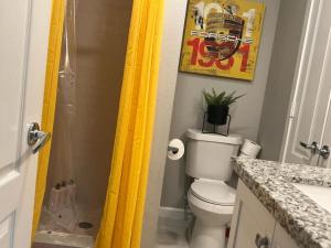 a bathroom with a toilet and a yellow shower curtain at 1 Galleria Downtown 3BR- Free Parking in Houston