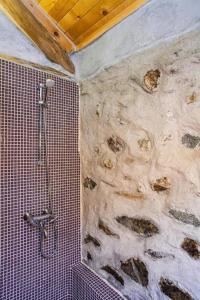 y baño con pared de piedra y ducha. en Подковите en Karlovo