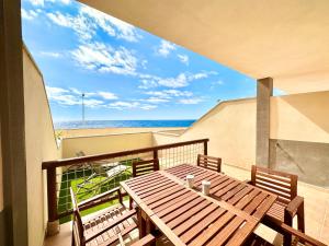 un tavolo in legno e sedie su un balcone con vista sulla spiaggia di Sunny Beach Villa - El Medano a El Médano