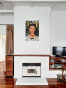 a living room with a fireplace with a painting on the wall at Redwood in Hikutaia