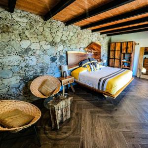 ein Schlafzimmer mit einem Bett und einer Steinmauer in der Unterkunft La Toscanía Tapalpa Resort & Agroturismo in Tapalpa