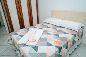 Una cama con edredón y dos toallas. en APTO - Espaço Village Completo - 2Q en Vitória