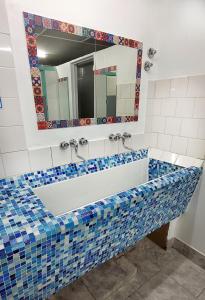 y baño con bañera de azulejos azules y blancos. en Lago Argentino Hostel en El Calafate