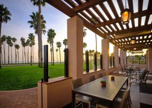 a patio with a table and chairs and palm trees at Hilton Santa Barbara Beachfront Resort in Santa Barbara