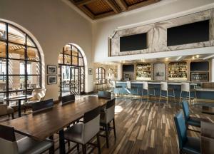 a dining room with a table and chairs and a bar at Hilton Santa Barbara Beachfront Resort in Santa Barbara