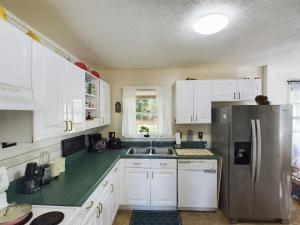 a kitchen with white cabinets and a stainless steel refrigerator at Pine Forest Zen Cottage - 10 Min to Fort Bragg in Fayetteville