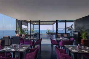 a restaurant with purple chairs and tables and the ocean at Radisson Hotel Colombo in Colombo