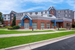 a large building on a street with a green lawn at MainStay Suites Fitchburg - Madison in Madison