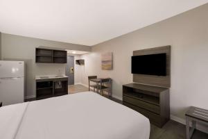 ミルウォーキーにあるSuburban Studios Milwaukee Airportのベッド1台、薄型テレビが備わるホテルルームです。