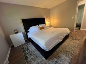 een slaapkamer met een groot wit bed en een tapijt bij Oasis Of Maple Grove in Maple Grove