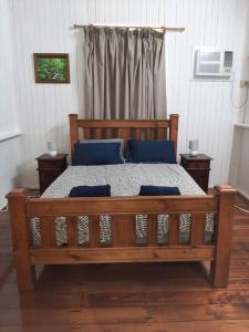 a wooden bed with blue pillows in a bedroom at Wangan Tropical Getaway 