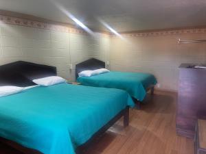 2 camas en una habitación con sábanas verdes en Provo Inn & Suites, en Provo