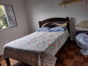 a bedroom with a bed with a blanket and a fan at Casa de Praia Ubatuba in Ubatuba