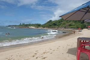 a beach with people in the water and an umbrella at Casa inteira, com sauna, piscina ozonizada, praia Enseada dos Corais, Cabo de Santo Agostinho, Pernambuco, Brasil in Cabo de Santo Agostinho