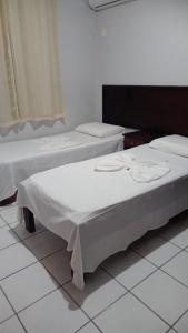 Duas camas num quarto com pisos em azulejo branco em Golden Dolphin Residence em Taperapuan perto Axé Moi em Porto Seguro